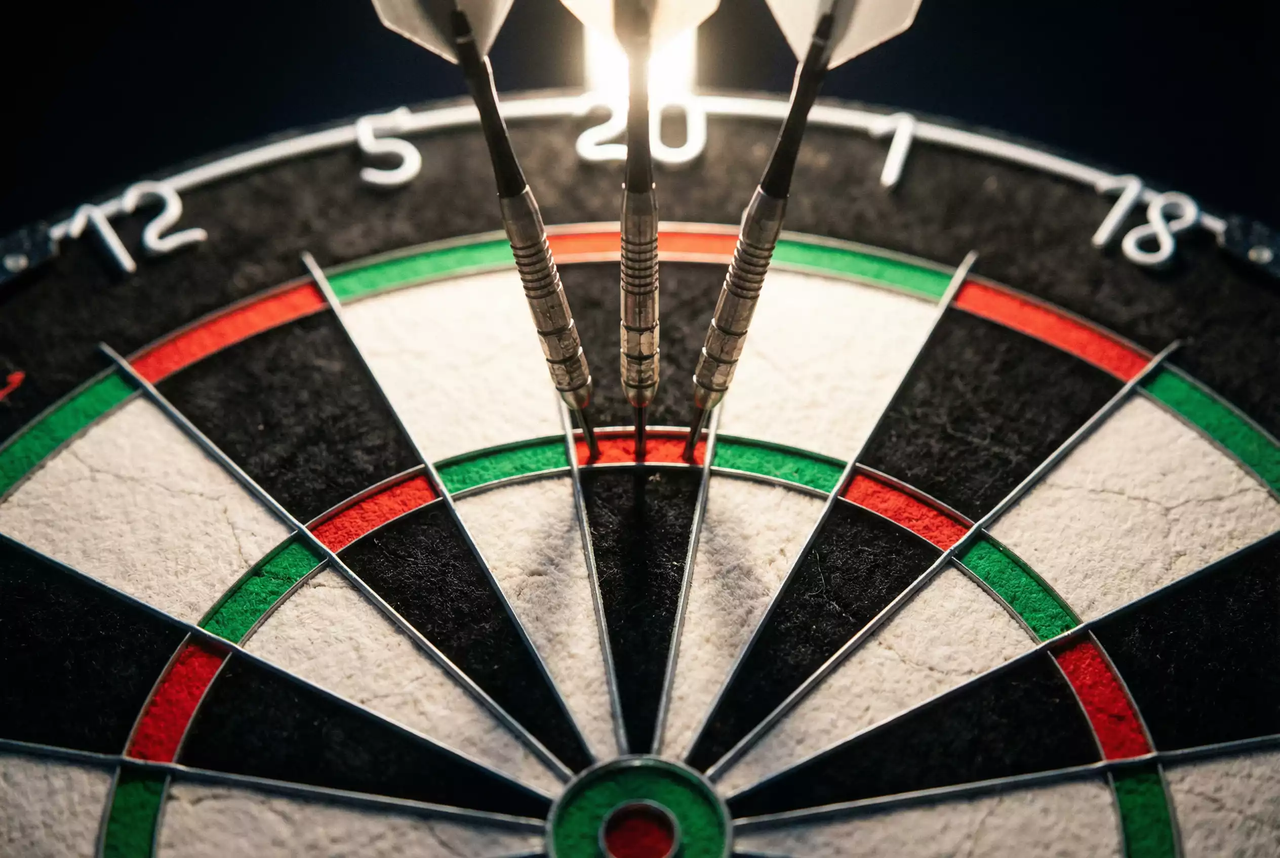 Darts-Wettarten erklärt — Dartpfeile auf einer Sisal-Dartscheibe mit beleuchteter Bühne